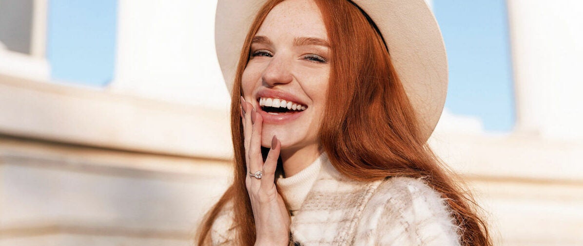 Mid-shot of stylish red head woman with lash extensions and smiling