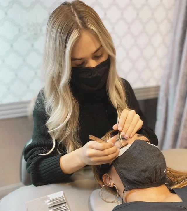 Woman adding lashes to a lash lounge customer