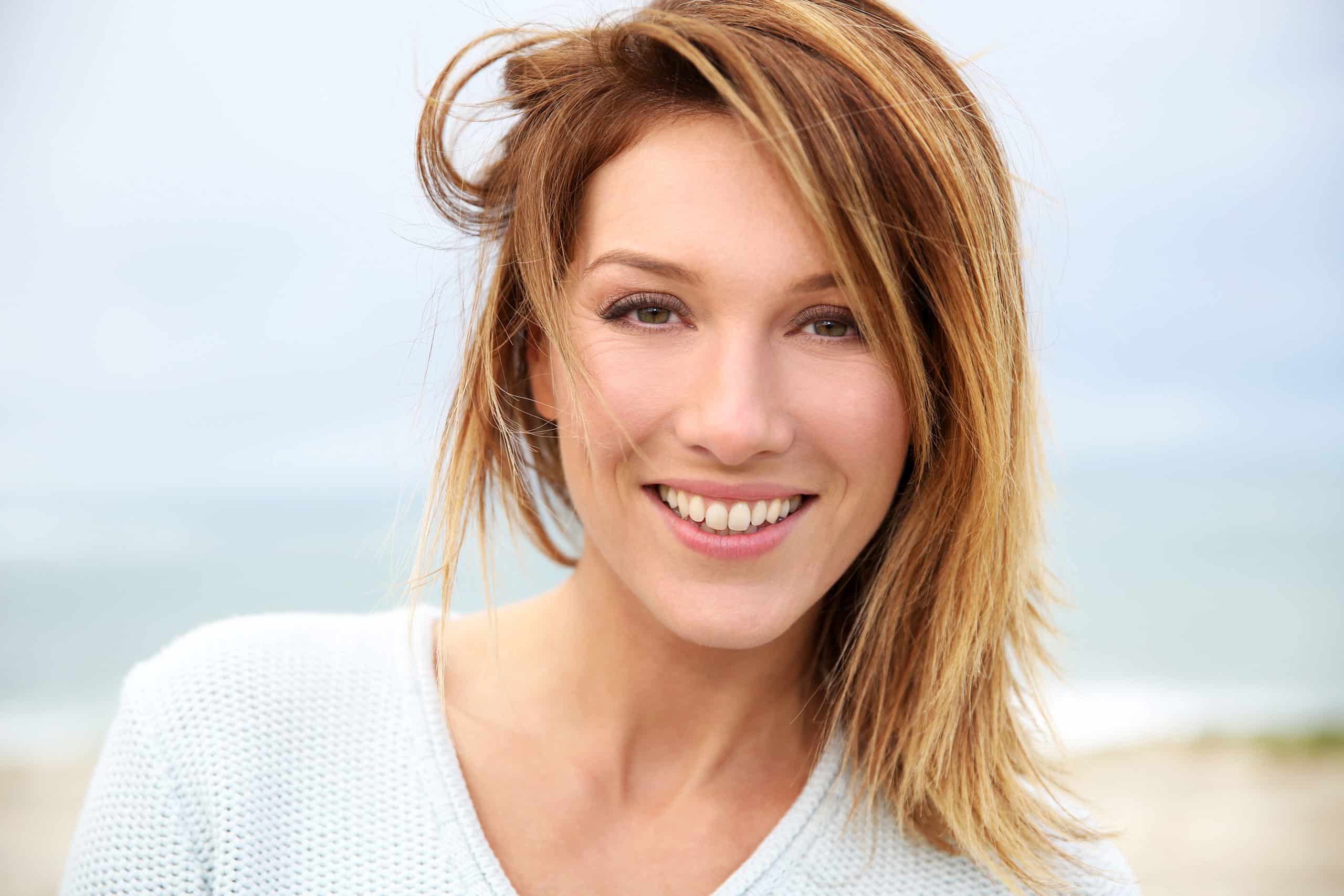 closeup of blond woman outside on beach with refreshed eyes and lash extensions