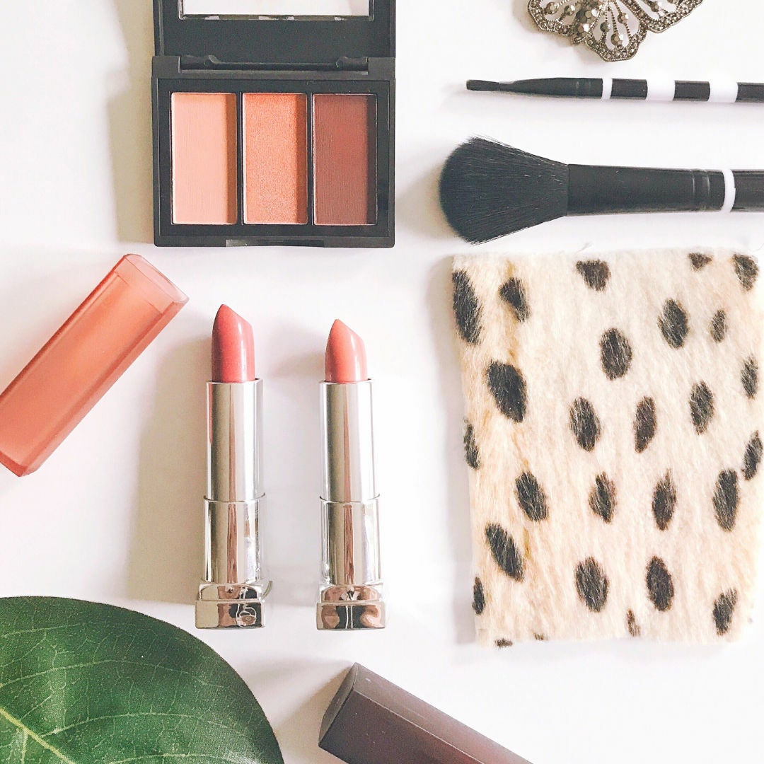 overhead view of makeup brushes, lipsticks, blushes and a makeup bag