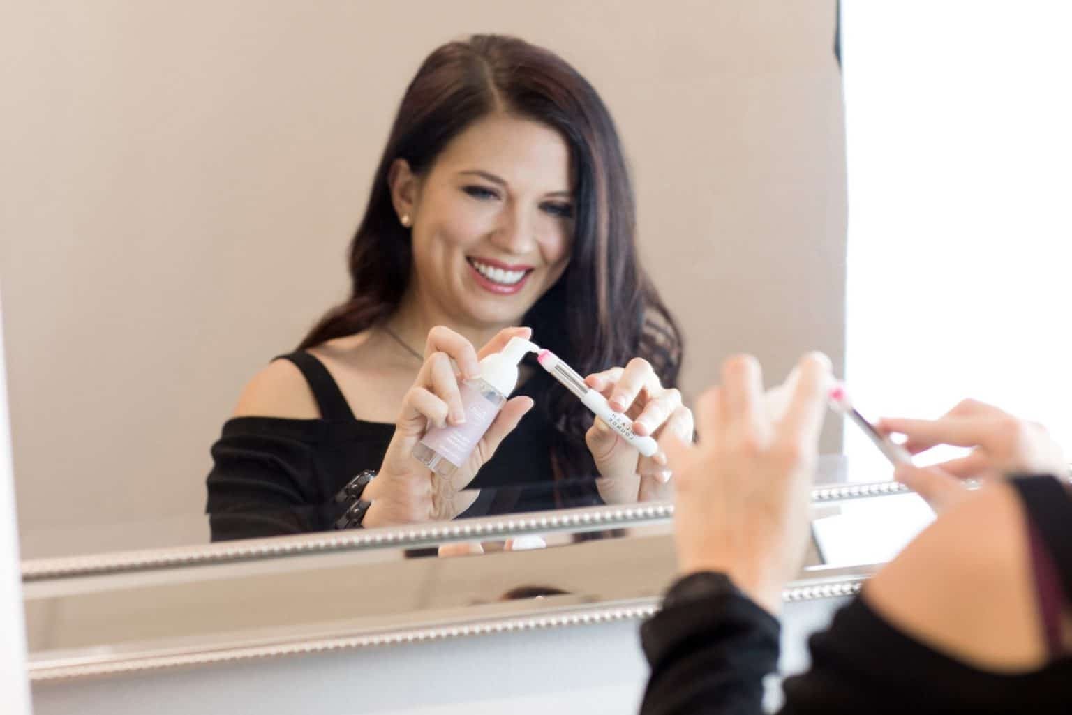 Woman pumping foaming lash cleanser onto a cleansing brush as part of her lash extension aftercare routine from The Lash Lounge.