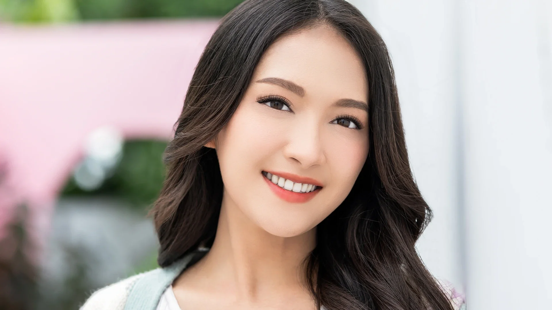 midshot of adult asian woman smiling outdoors with hybrid lash extensions