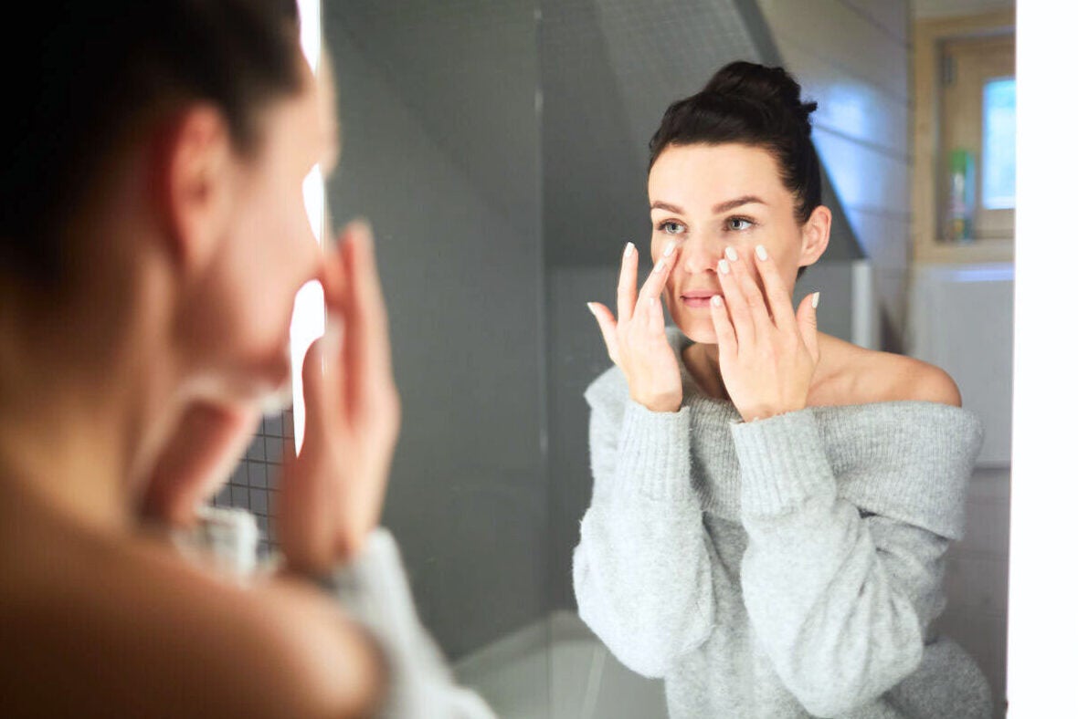 mid shot of woman touching her face in mirror