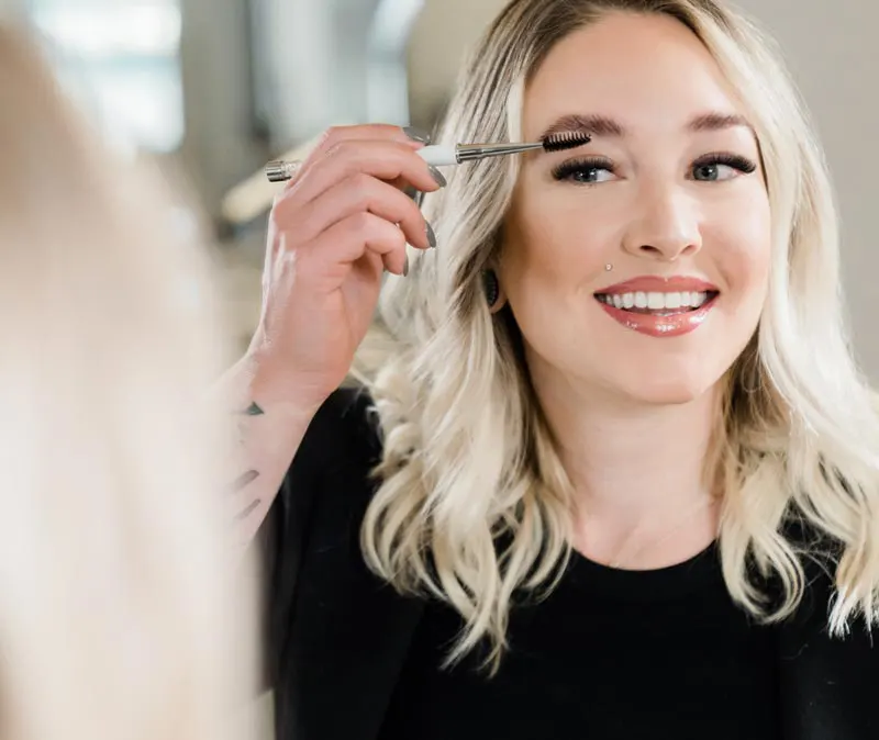 Woman brushing brows after an eyebrow lamination service.