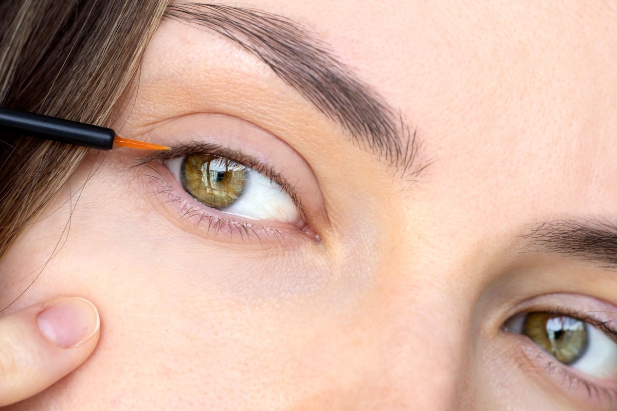 close-up of woman applying a lash serum