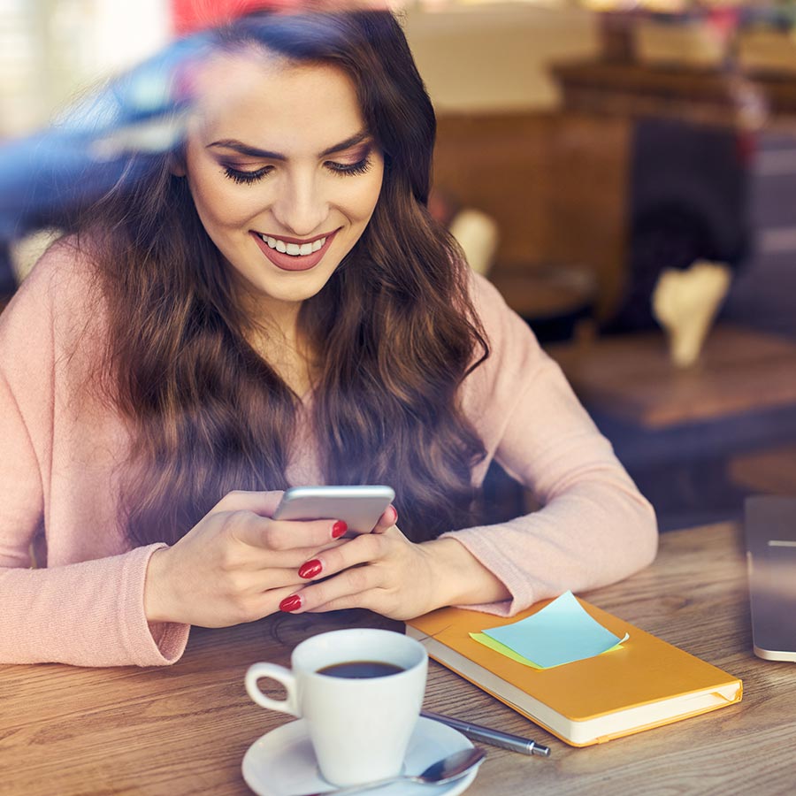 Woman at coffee shop viewing phone with permanent makeup done by The Lash Lounge