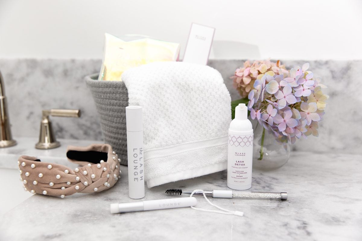 marble bathroom counter with flowers and lash extension aftercare products