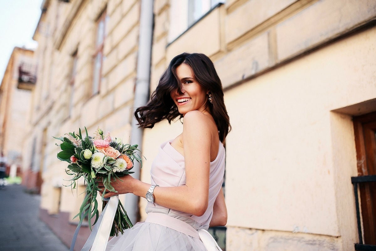 Bride outdoors smiling with bouquet.