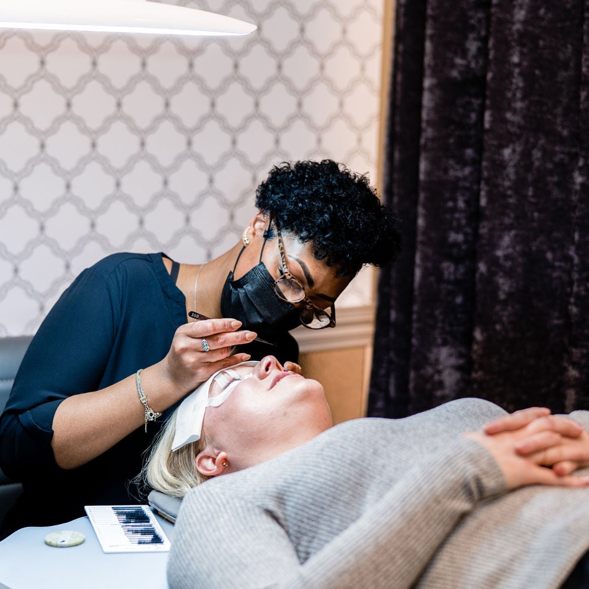 Lash stylist applying lash extensions to a Lash Lounge guest