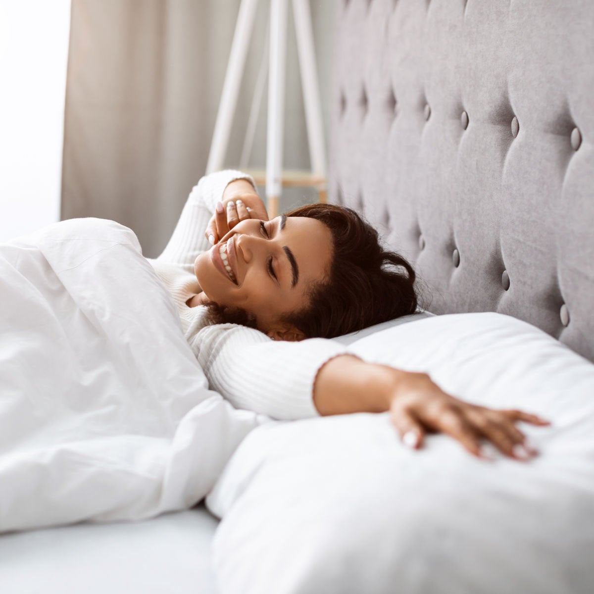 woman smiling and stretching in bed