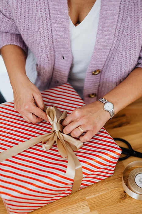 woman tying ribbon on a holiday gift